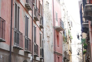 Una calle estrecha con edificios que tienen balcones y persianas.