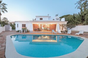 Et moderne hus med swimmingpool, udendørs siddepladser og en patio.
