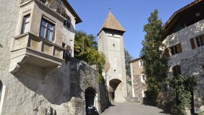 Uma rua estreita com edifícios de pedra, uma torre e um arco.