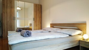 Quarto com cabeceira de madeira, um espelho grande e mesa de cabeceira com abajur.