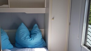 A compact bedroom with a bunk bed, a wardrobe, and a window with blinds. - Mobile Home in Renesse at the 4-star Camping de Brem (Renesse)