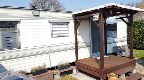 A mobile home with a covered porch and a sign labeled "MM1". - Mobile Home in Renesse at the 4-star Camping de Brem (Renesse)