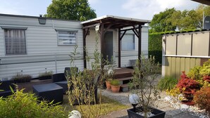 A mobile home with a patio area, outdoor seating, and various potted plants. - Mobile Home in Renesse at the 4-star Camping de Brem (Renesse)