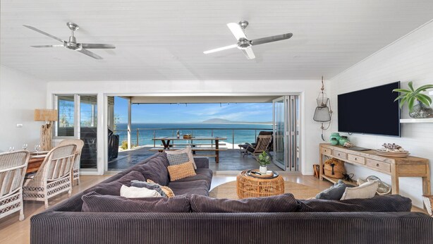 Ein geräumiges Wohnzimmer mit einer großen Couch, einem Essbereich und einem Balkon mit Meerblick.