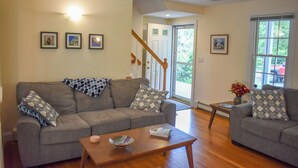 A living room with two grey sofas, a wooden coffee table, and framed pictures on the wall.