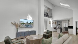 Un espacio habitable amplio con un diseño moderno, que incluye un sofá grande, una mesa de centro y un televisor montado en la pared.