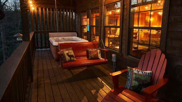 A wooden deck with a hot tub, a wooden bench, and a red Adirondack chair. - Best Price!!! Cabin with Mountain Views, Hot Tub, Sleeps 6, 10 Min to Parkway! (Sevierville)