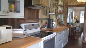 Eine Küche mit Mikrowelle, Herd und Backofen. Es gibt eine Holz Arbeitsplatte und einen Essbereich mit Tisch und Stühlen.