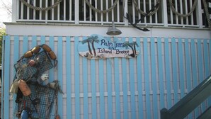 Ein blau-weißes Gebäude mit einem Schild, auf dem steht: "Palm Trees and Island Breeze".