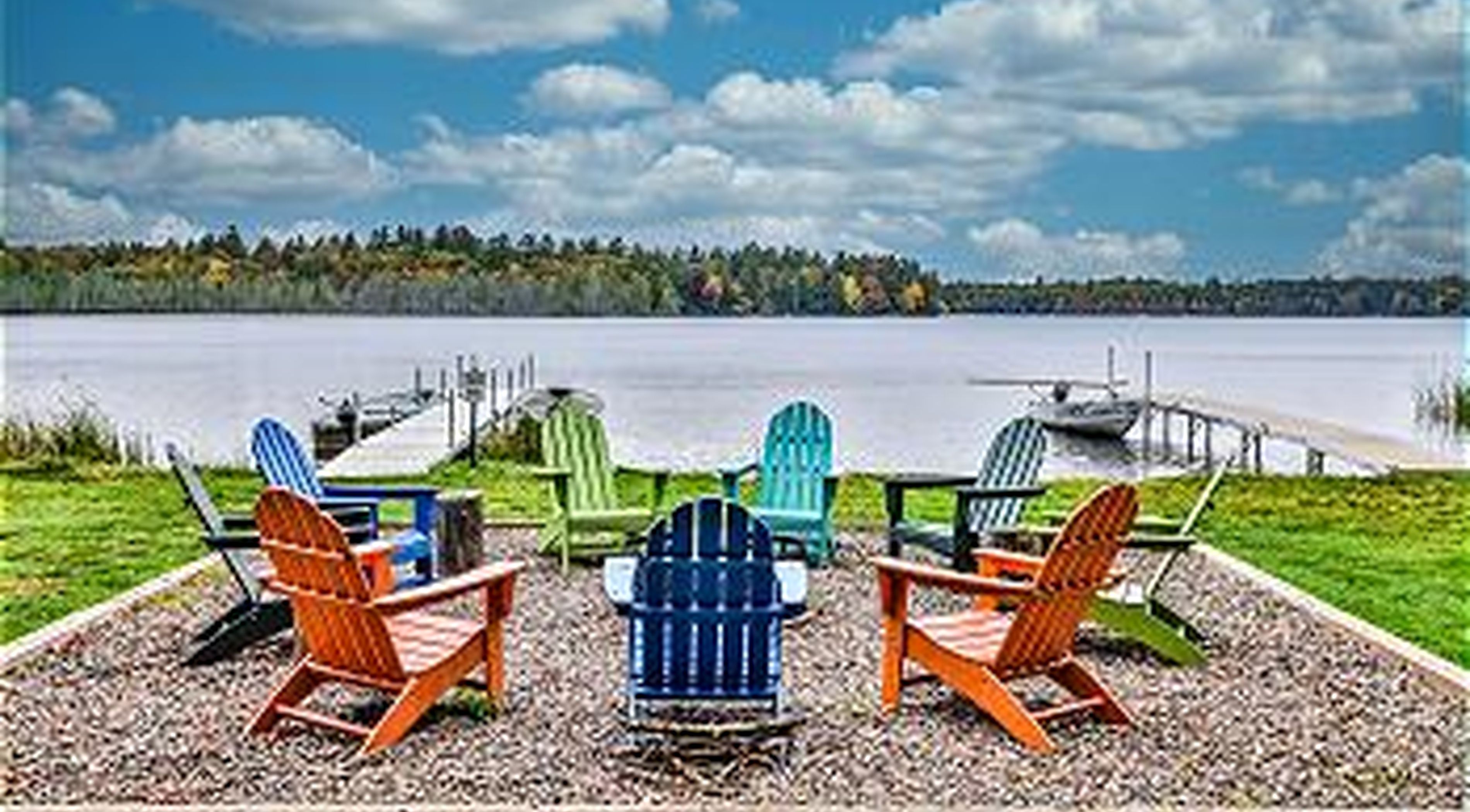 A lakeside seating area with Adirondack chairs and a dock.