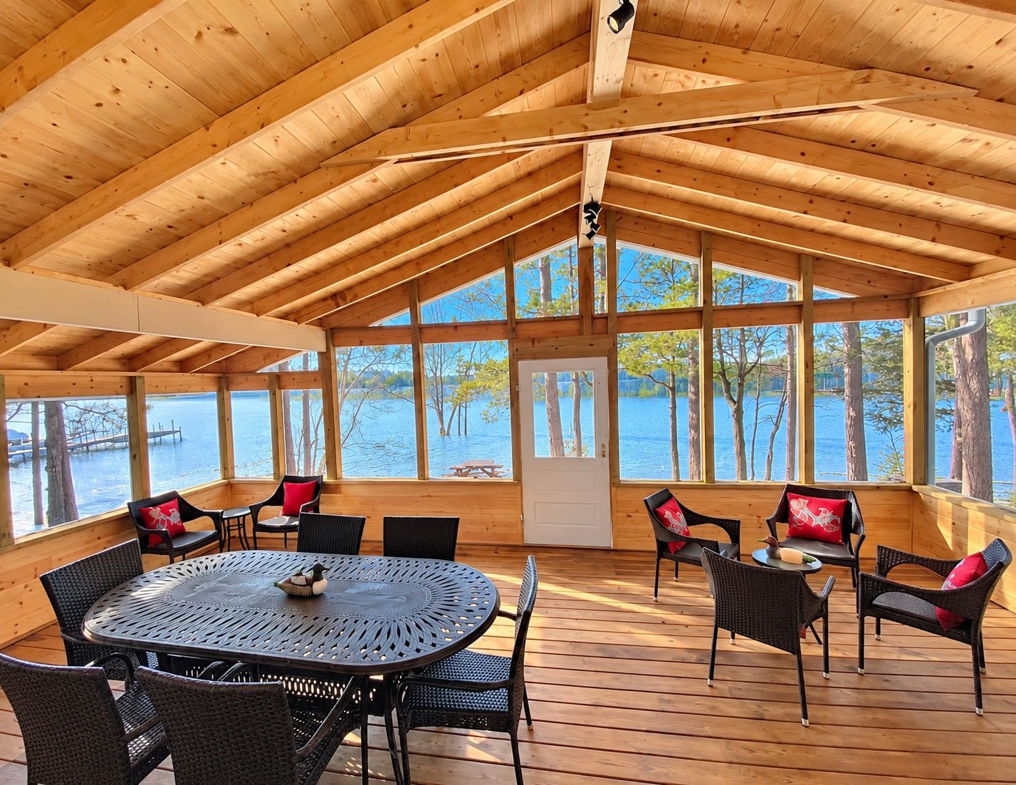 A covered outdoor seating area with a view of a lake and dock.