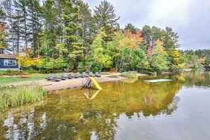 Une zone au bord du lac, avec un quai, des chaises longues et des kayaks.