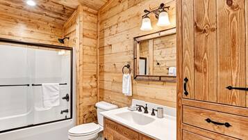 A wooden-paneled bathroom with a bathtub, toilet, sink, and vanity.