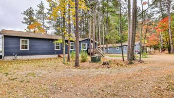 A row of cabins with a dirt ground and trees with autumn leaves.