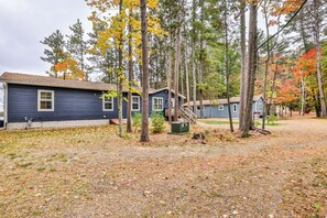 Une rangée de cabanes, avec un sol en terre et des arbres aux feuilles d’automne.