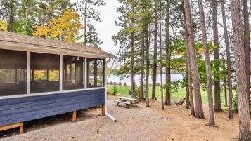 A cabin with a covered porch, a picnic table, and a hammock.
