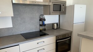 Una cocina moderna con microondas, horno y hervidor sobre la encimera.