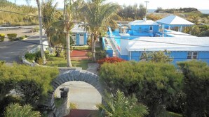 A coastal property with a blue building, a stone archway, and palm trees. - Blue Horizons Guest House - Room # 7 (Hamilton)