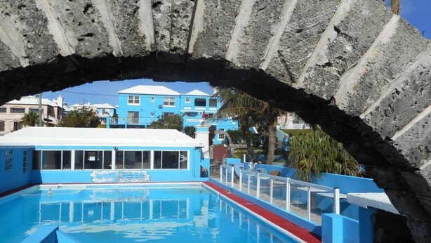 A pool area with a clear view of a building in the background. - Blue Horizons Guest House - Room # 7 (Hamilton)