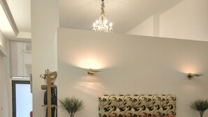 A bedroom with a large bed, a chandelier, two wall-mounted lamps, a bedside table, and a nightstand. - Beachside apartment (Santander)