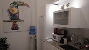 A compact kitchen with a water dispenser, a microwave, a toaster, and a sink. - Beachside apartment (Santander)