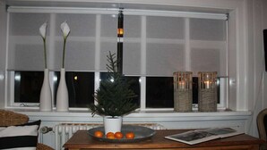 Un comò in legno con un vaso di fiori bianchi, una piantina in vaso e un vassoio con arance.