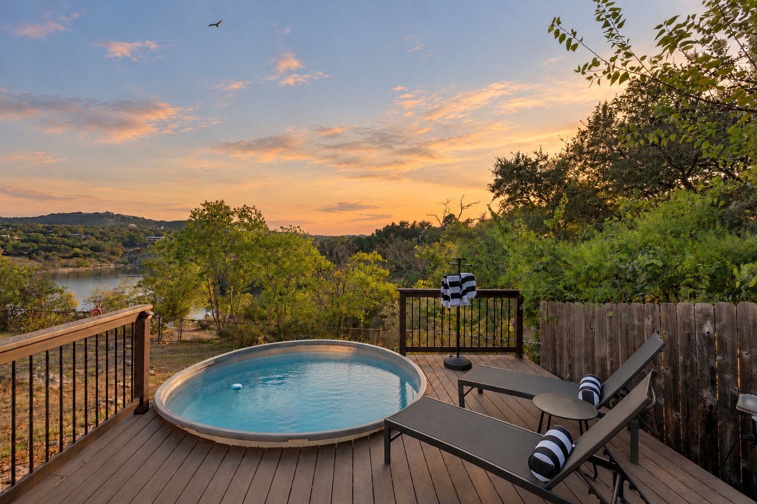Un jacuzzi en una terraza de madera con vista a un lago y colinas.