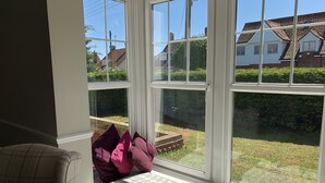 Ein Erker mit eingebauter Bank, Blick auf einen Garten und ein Haus im Hintergrund.