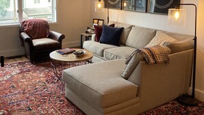 Ein Wohnzimmer mit einer Couch, einem Couchtisch, einem gemusterten Teppich, einem Sessel und Bildern an der Wand.