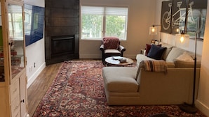 Ein Wohnzimmer mit Kamin, einer Couch, einem Couchtisch und einem gemusterten Teppich.