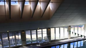 Ein großzügiger Innenbereich mit großen Fenstern, einem Pool und Sitzgelegenheiten am Pool.