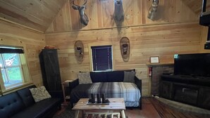 L'intérieur d'une cabane en rondins, avec un canapé, une table basse, une cheminée et des bois de cerf accrochés au mur.