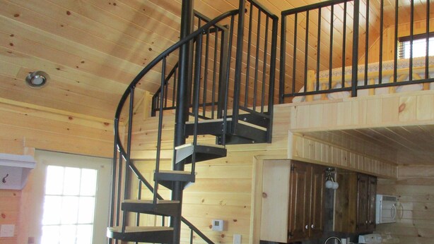 Un intérieur en bois avec un escalier en colimaçon, une cuisine dotée de meubles en bois et une porte avec une fenêtre.