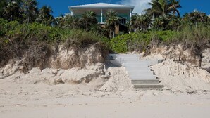 A beachfront property with a staircase leading to a house surrounded by palm trees and vegetation. - Lux Beachfront House W/ Private Pool on Banks Rd. Walk to Tippy's! (Governors Harbour)