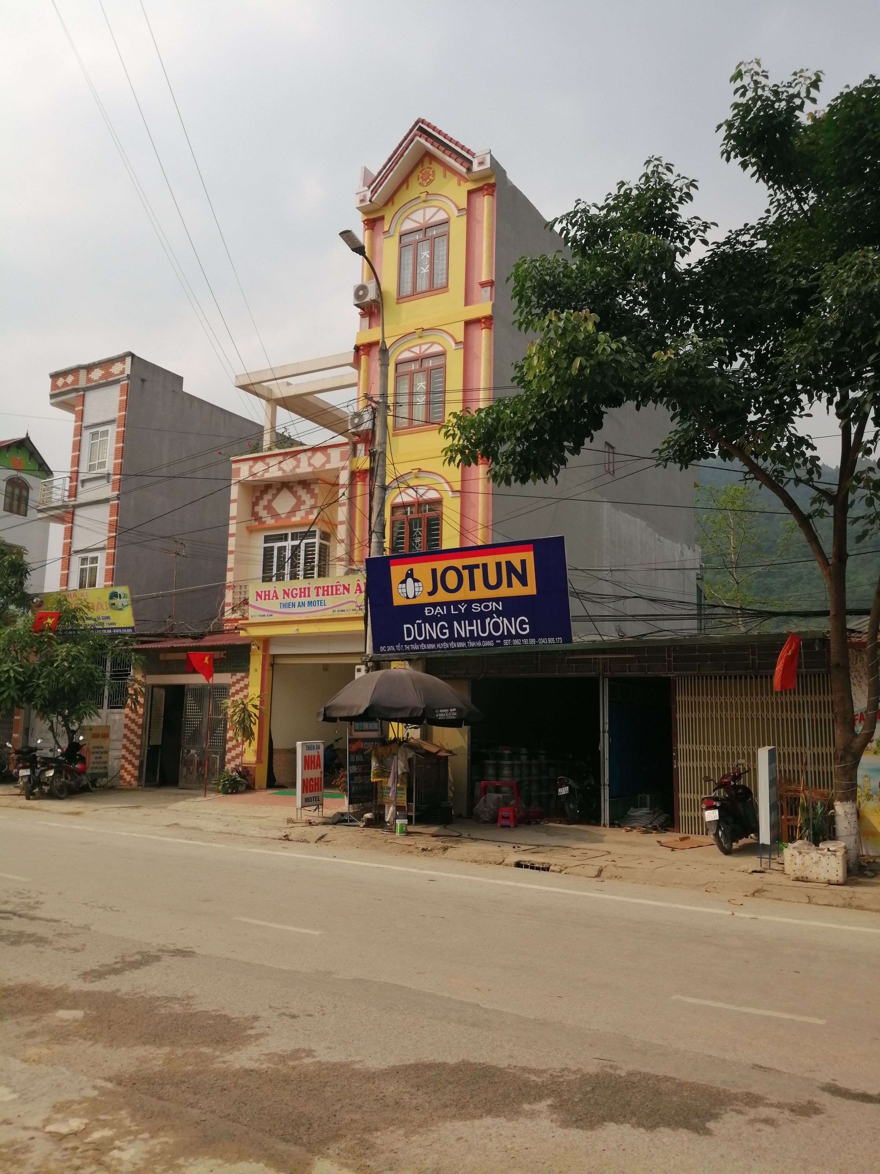 A building with a prominent sign for 'JOTUN DUNG NHAUONG' and a visible entrance with a covered area.