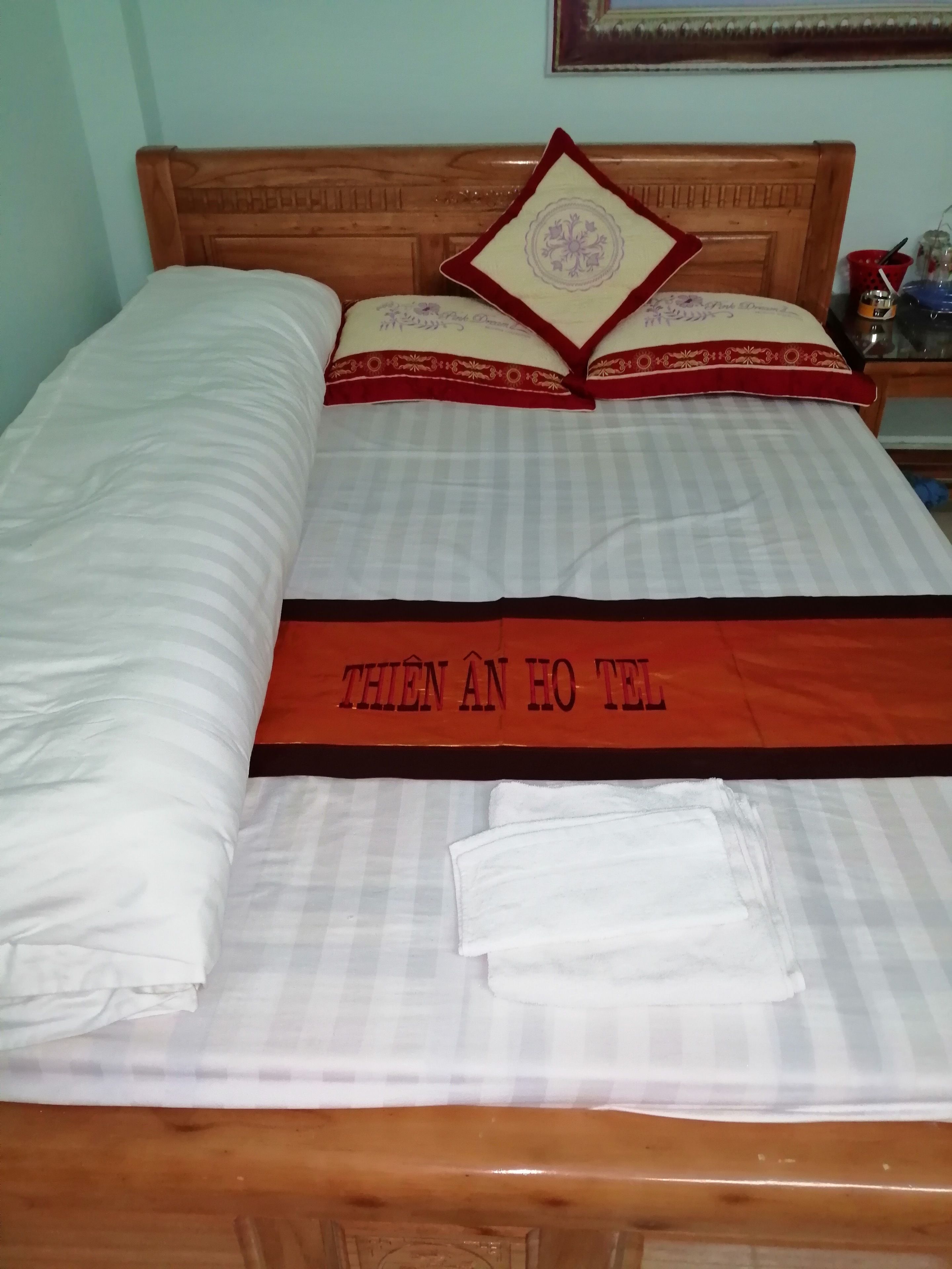 A neatly made bed with a striped bedspread and a red and white pillow with a decorative pattern.