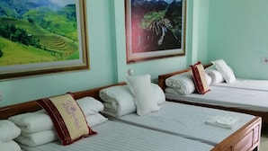 Habitació d'hotel amb dos llits, cadascun amb tovalloles blanques ben arremegades i un coixí decoratiu vermell.