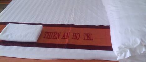 A wooden bed with white bedding and a red and white blanket with text.