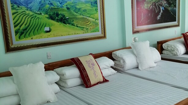Habitació d'hotel amb dos llits, cada un amb roba de llit blanca i un coixí decoratiu vermell. Hi ha dos quadres de paisatges emmarcades a les parets.