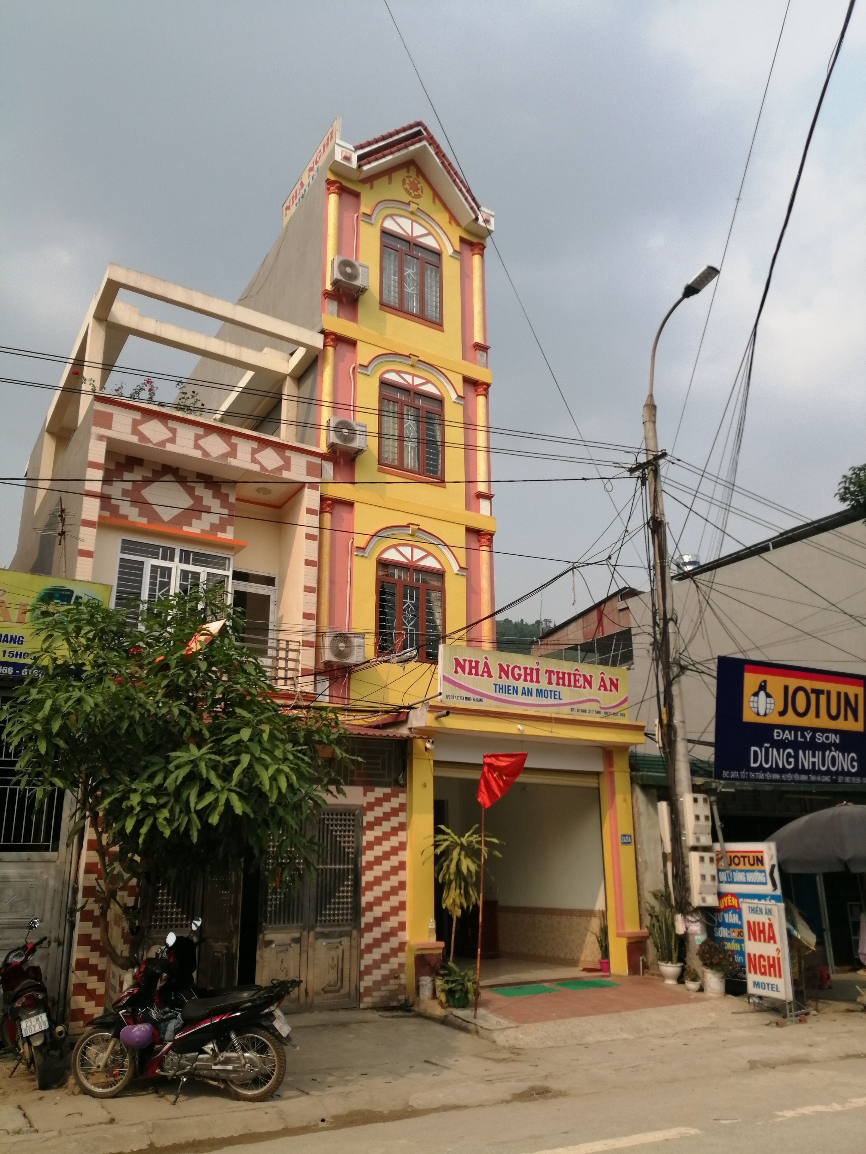 Ein mehrgeschossiges Gebäude mit einer gut sichtbaren Schilder für das Motel 'NHA NGHI THIEN AN'.