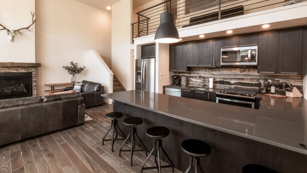 A modern kitchen with a central island, stainless steel appliances, and a mezzanine level. - The Salida Opera House Loft (Salida)