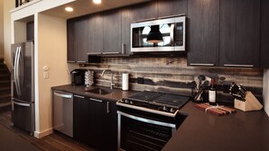 A modern kitchen with dark wood cabinets, stainless steel appliances, and a built-in microwave. - The Salida Opera House Loft (Salida)