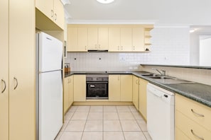 A compact kitchen with a refrigerator, oven, dishwasher, and a sink.