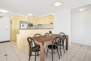 Eine moderne Küche mit Essbereich, ausgestattet mit einem Holztisch, Stühlen, einer Mikrowelle und einem Kühlschrank.