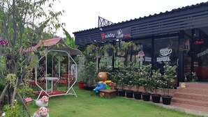 Een tuin met een schommel, een groot knuffelbeerbeeld en plantenpotten.