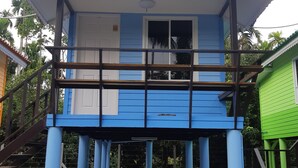 Een blauw-wit gebouw met een balkon, een trap en een groene constructie in de buurt.