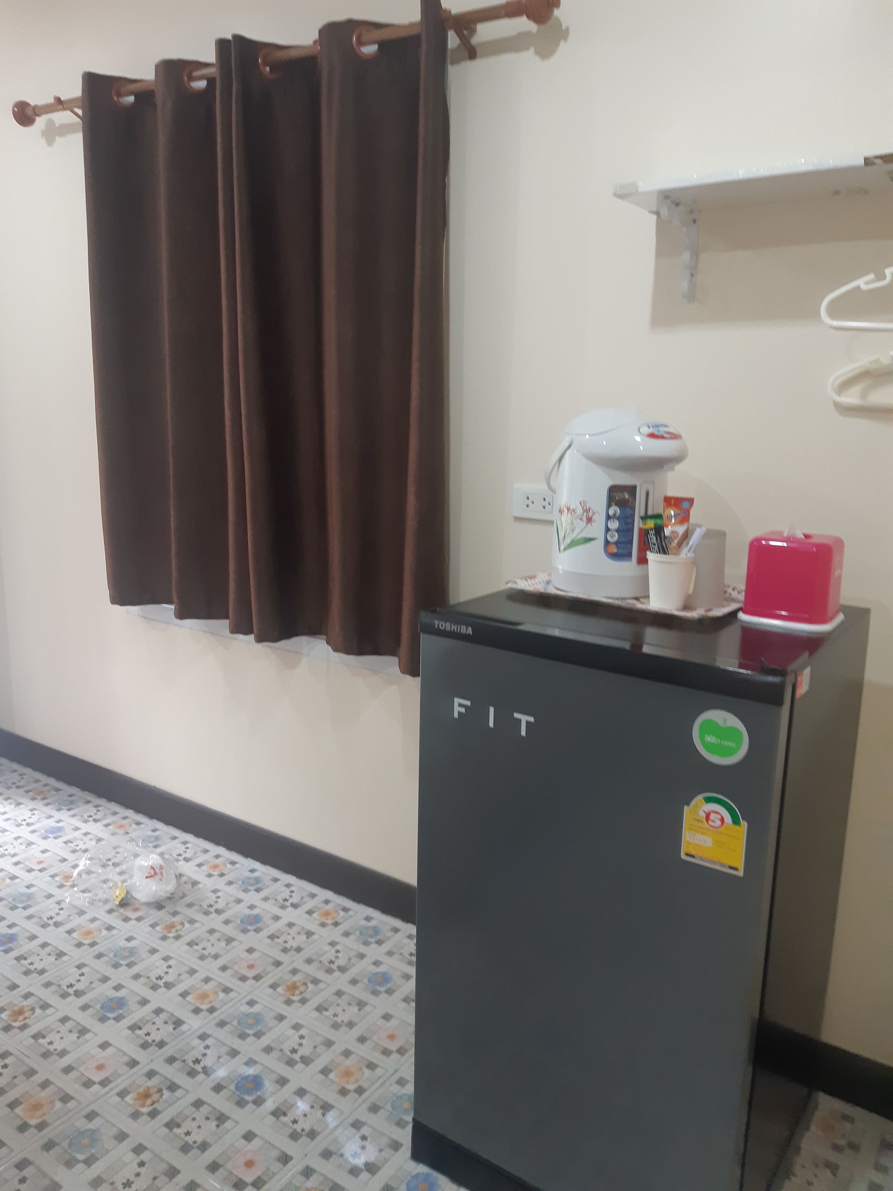 A room with a fitted refrigerator, a coffee machine, and a pink container on top.