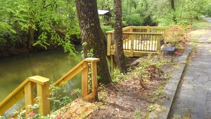A wooden deck with a railing overlooking a calm river, surrounded by lush greenery. - Cleveland Home w/ South Saluda Fishing Access (Cleveland)