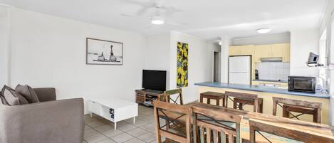 A modern living room with a sofa, TV, and artwork on the wall.