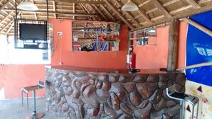 A bar area with a stone counter, a television mounted on the wall, and a fire extinguisher. - United Motel Entebbe (Entebbe)